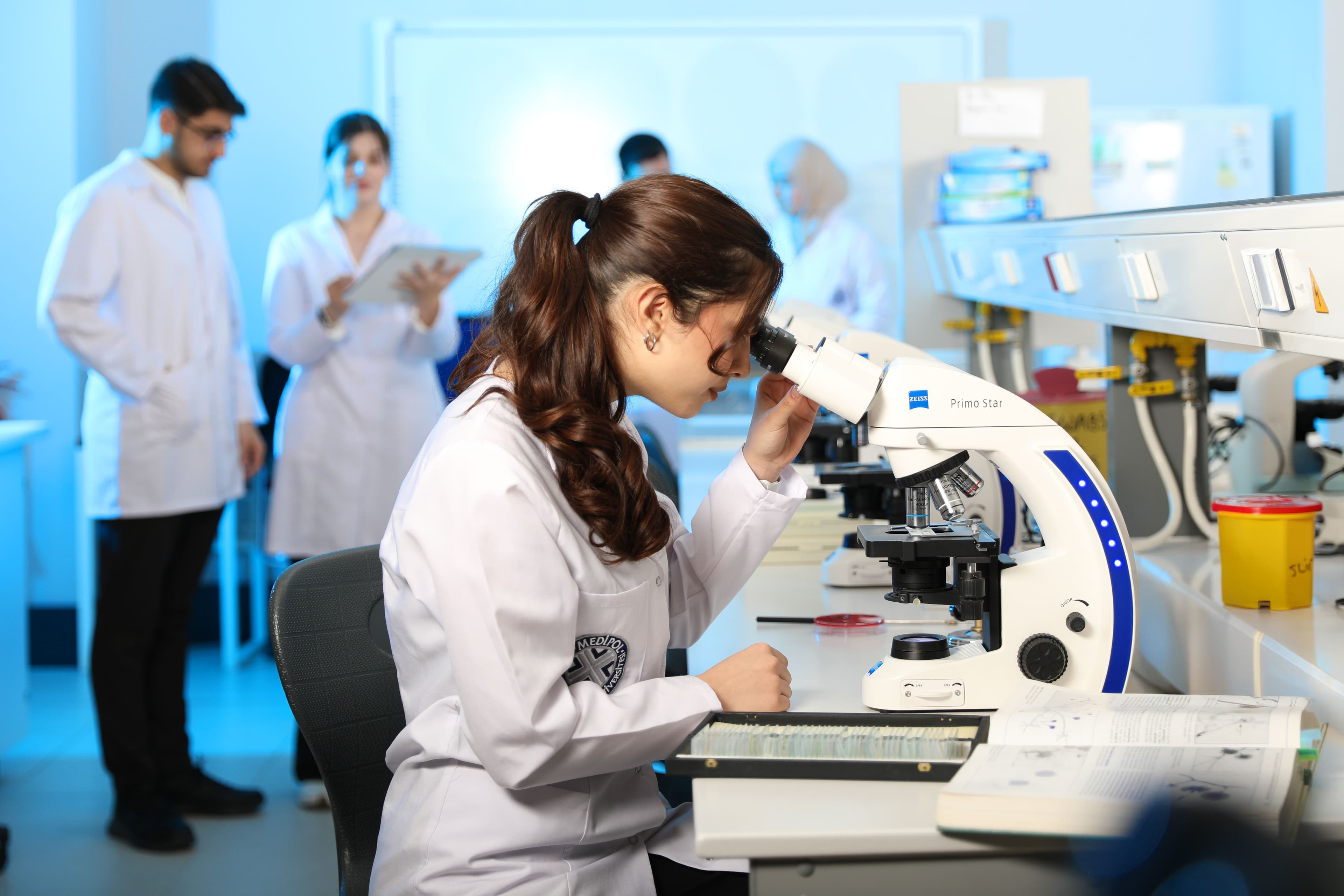 Scientist in a lab coat using a microscope in a modern research laboratory